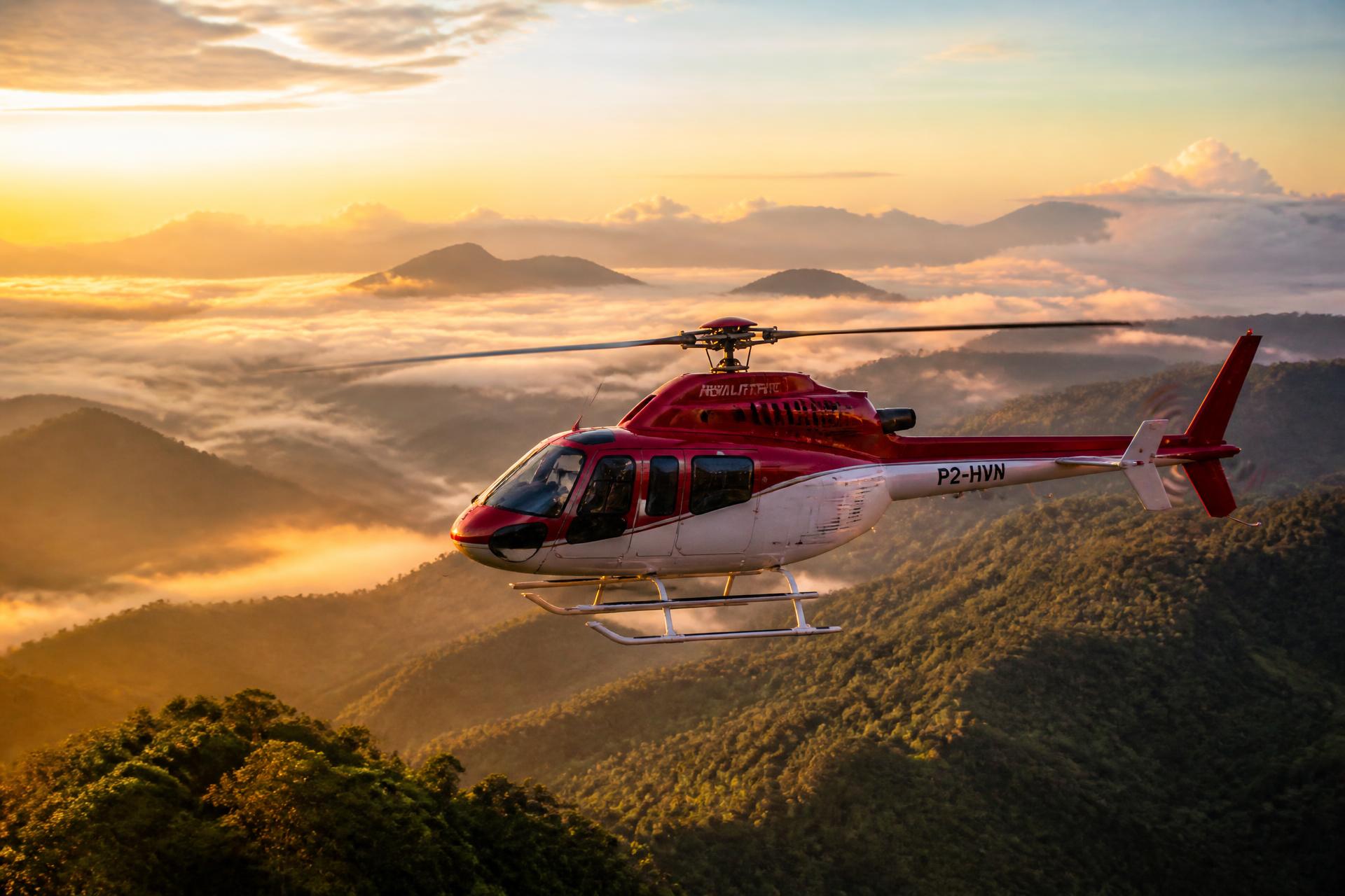 Helicopter flying over Papua New Guinea mountains at sunrise